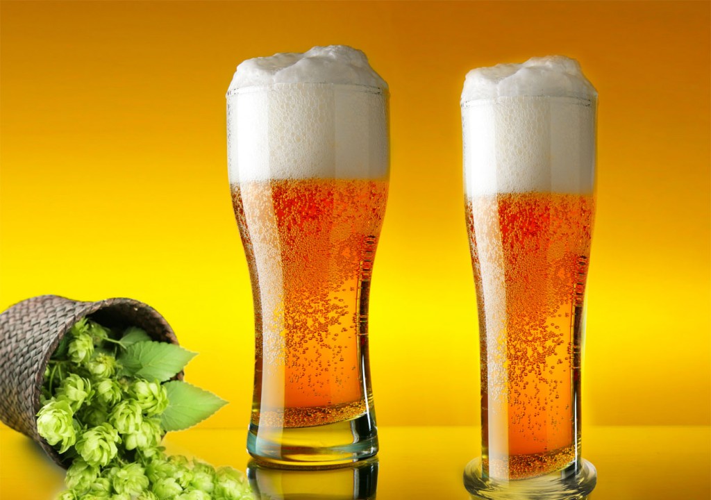 Glass of beer close-up with froth over yellow background